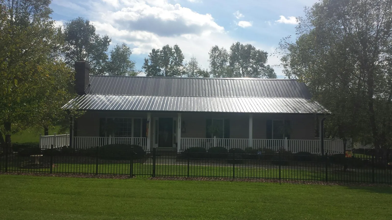 Gray metal roof on a brick ranch with a full width front porch — Gutter Guard Installation work by our crew in Sun Valley