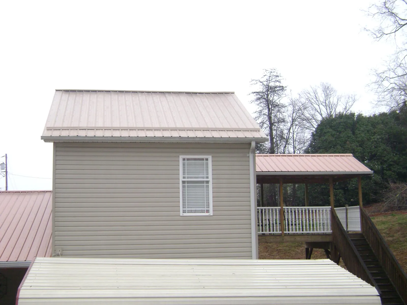 Tan metal roofs on a two story addition and attached porch, from a Roof Replacement job in Sun Valley